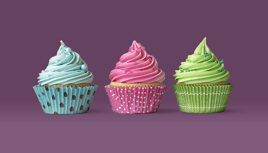 Tre cupcakes mot en lila bakgrund, en med blå, en med rosa och en med grön frosting.
