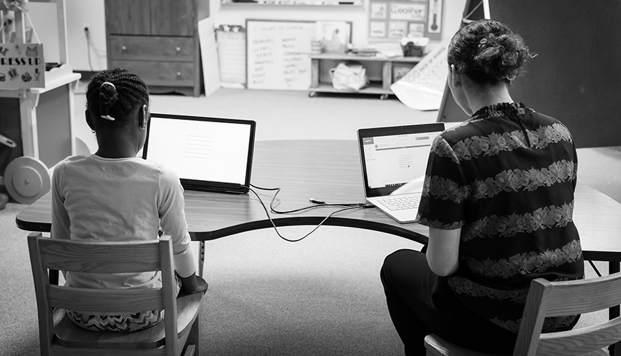 Elev och lärare arbetar vid datorer.