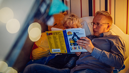 En man läser en bok för ett barn.