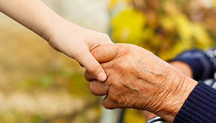 En yngre persons hand och en äldre persons hand som håller i varandra