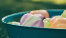 Närbild på vattenballonger i olika färger som ligger i en balja
