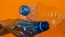 Ihopknycklade plastflaskor på orange bakgrund