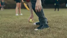 Person som plockar upp en boll från en gräsmatta