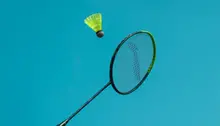 Badmintonrack och boll med blå himmel i bakgrunden