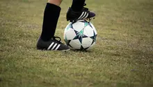 Barnfötter med fotbollsskor och strumpor och fotboll