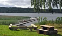 Grillplats vid sjö och brygga med sittplatser o träbänkar bredvid