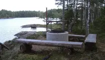 Grillplats med bänkar runt vid en sjö