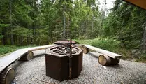 Grillplats i skogen med träbänkar runt om