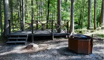 Grillplats bredvid ett trädäck med staket i skogen