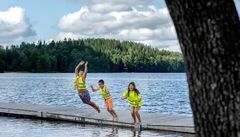 Tre barn som hoppar i vattnet från en brygga